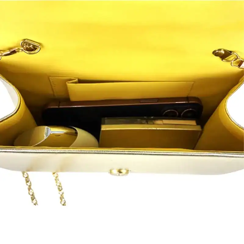 Guld satinclutch med innehåll, mobil och plånbok i interiören.