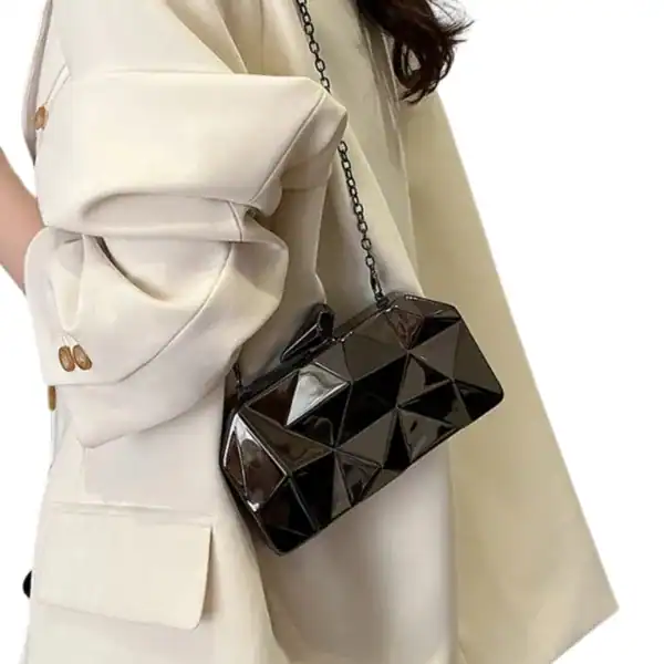 Guldig geometrisk clutch i svart, elegant axelväska med kedjehängare.