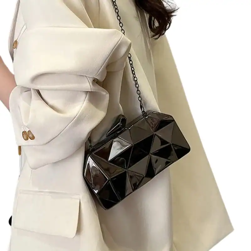 Guldig geometrisk clutch i svart, elegant axelväska med kedjehängare.