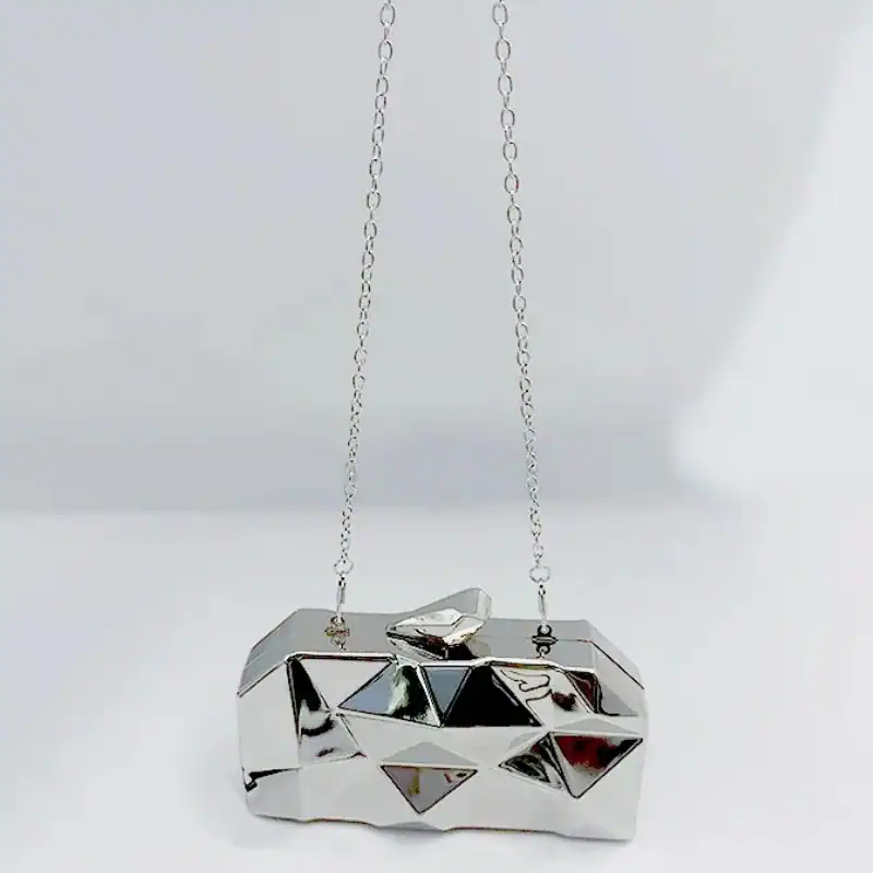 Guldig geometrisk clutch med kedja, perfekt för fest och kväll.