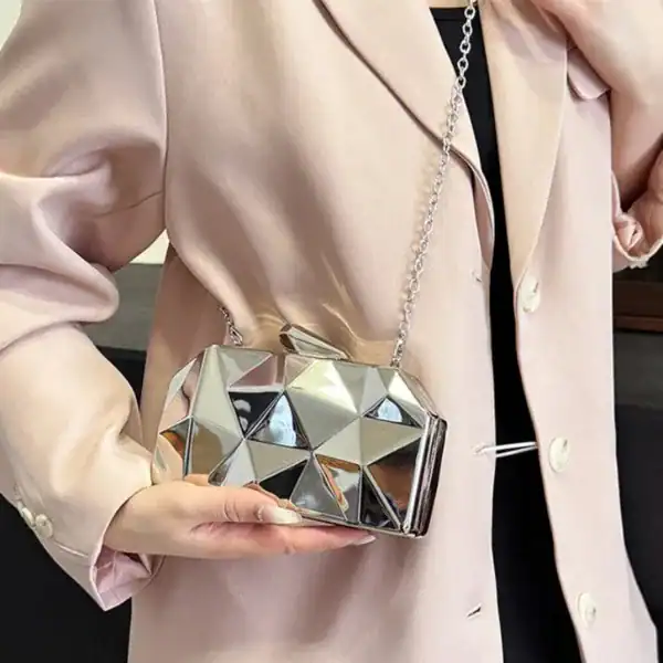 Guldig geometrisk clutch med silverfärgad kubisk design och kedjehängare.