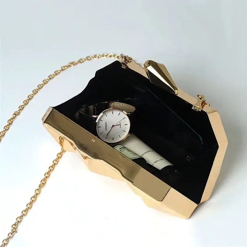 Guldig geometrisk clutch med kedja, innehåller klocka och flaskor.
