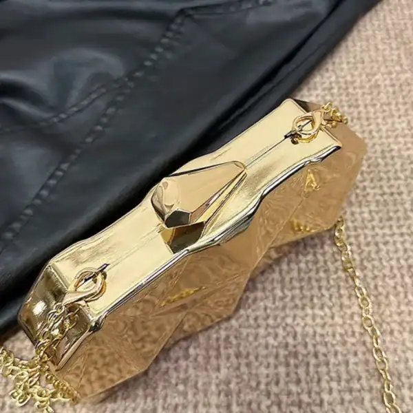 Guldig geometrisk clutch med kedja och detaljerad yta.