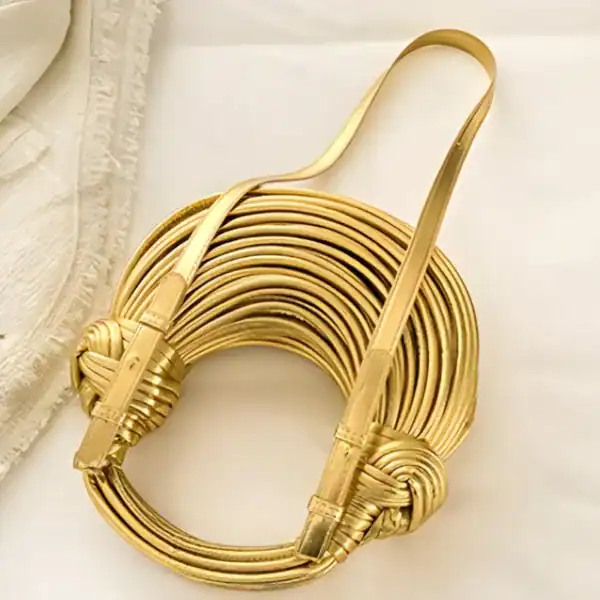 Guldig knuten väska, elegant guldfärgad axelväska med knutdetaljer och läderrem.