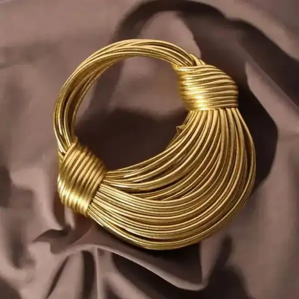 Guldig knuten väska med eleganta ringform och glittrande guldtoner.