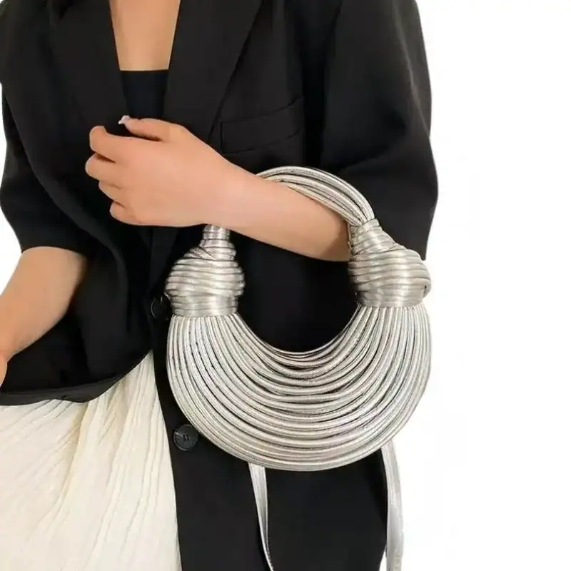 Guldig knuten väska i silver, modehandväska med knutad handtag och eleganta design.