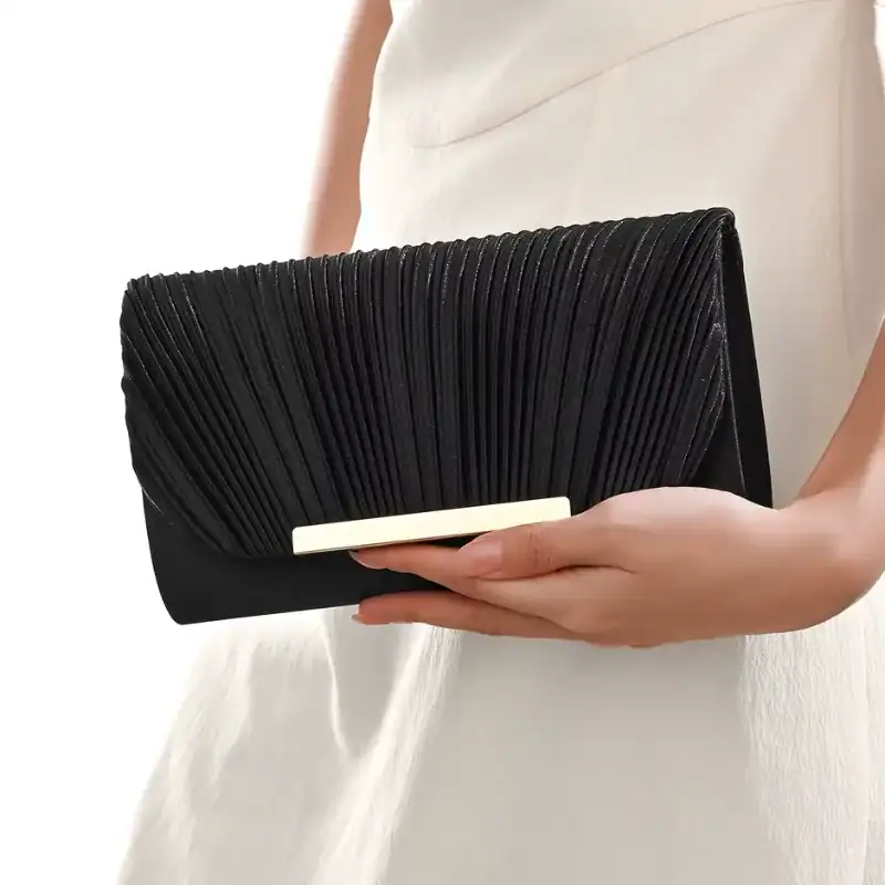 Guldig plisserad clutch i svart, elegant handväska med gyllene snäcka.