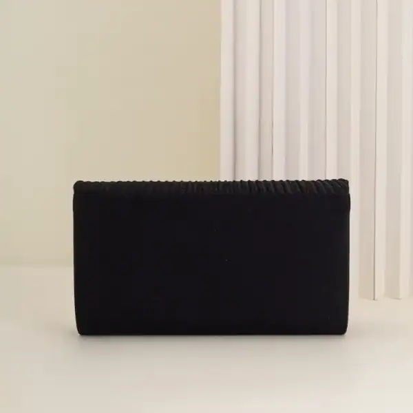 Guldig plisserad clutch i svart, elegant axelväska med glittrande detaljer.