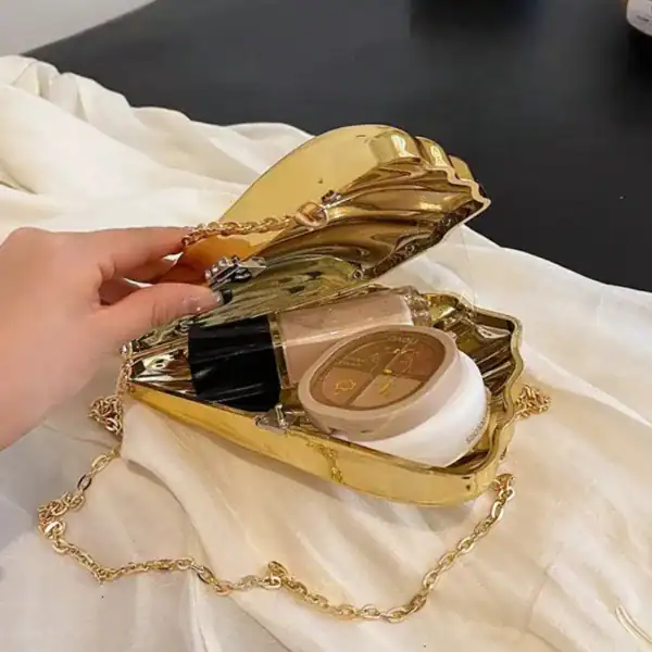 Guldig Axelväska med öppen lock och kosmetik, gyllene kedjehängare.