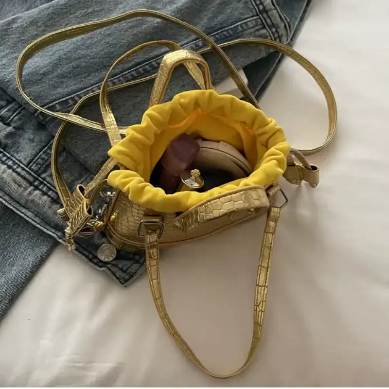 Guldväska med gul inre och krokodiltextur, perfekt för städning och mode.