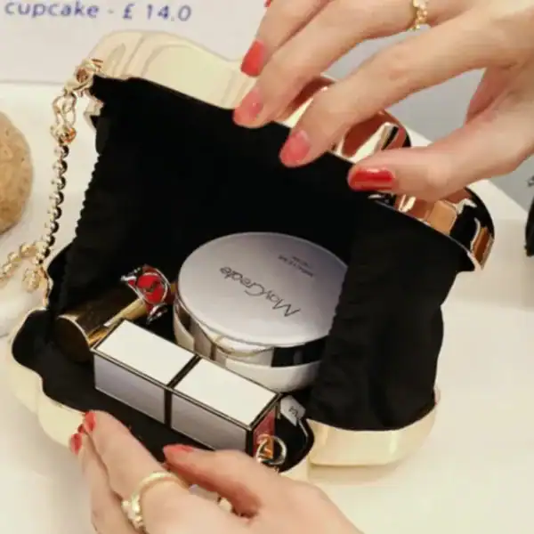 Silver handväska med makeup, öppen och fylld med kosmetikprodukter.