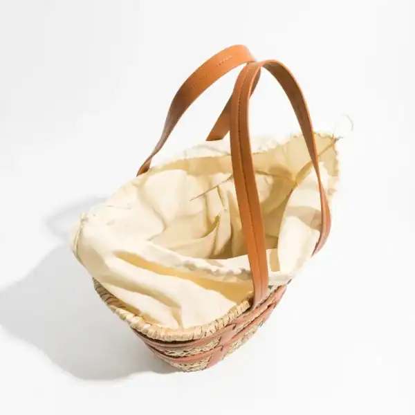 Liten korgväska med läderhandtag och beige inre, perfekt för daglig användning.