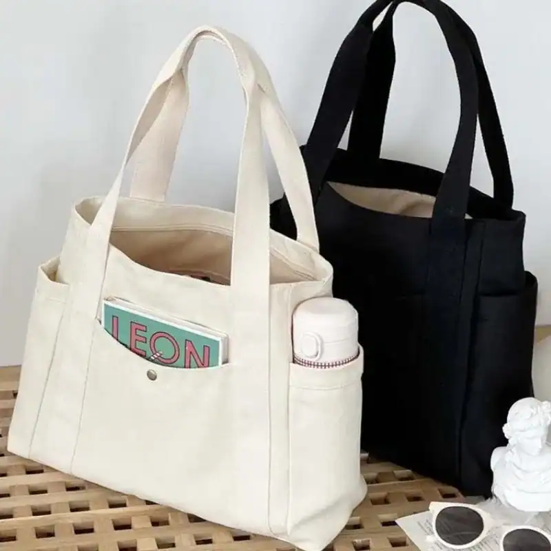 Krämvit canvas shoppingväska med fickor och vattenflaska.