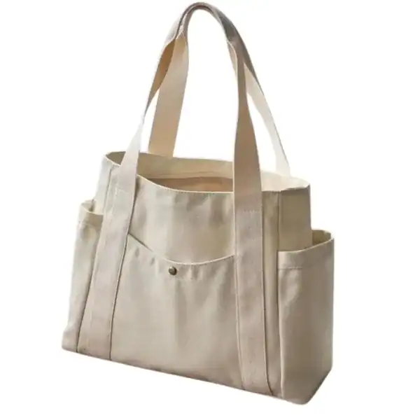 Krämvit canvas shoppingväska med sidopåsar och handtag.