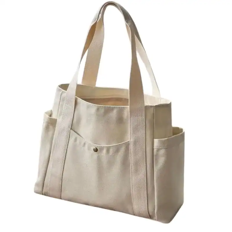 Krämvit canvas shoppingväska med sidopåsar och handtag.