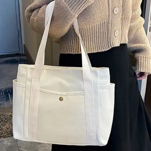 Krämvit canvas shoppingväska med långt handtag och framsida ficka.