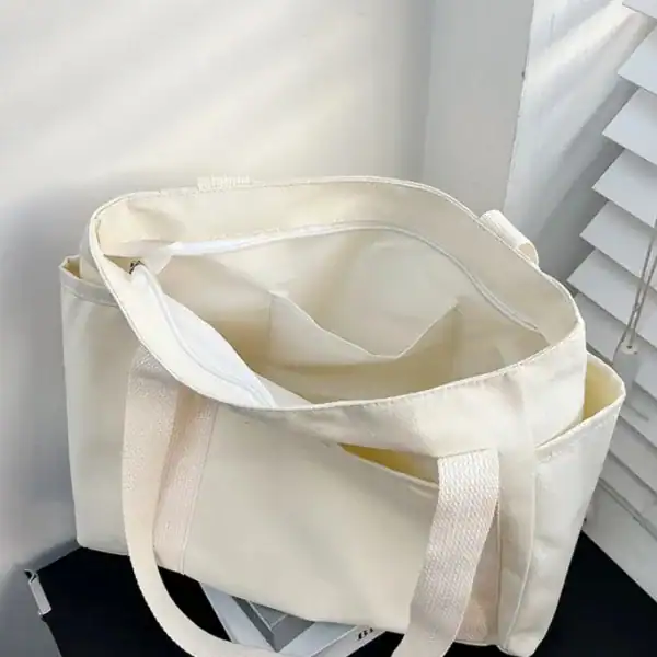 Krämvit canvas shoppingväska med långt handtag och stor kapacitet.