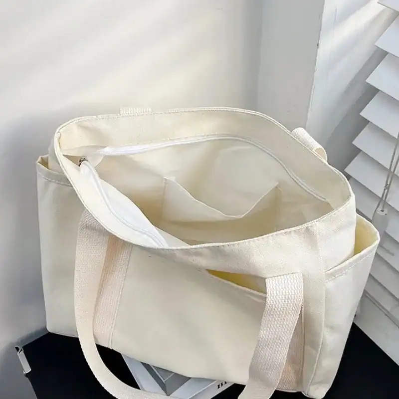 Krämvit canvas shoppingväska med långt handtag och stor kapacitet.