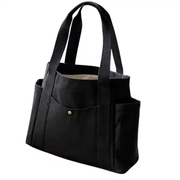 Krämvit canvas shoppingväska, svart, med fickor och handtag.