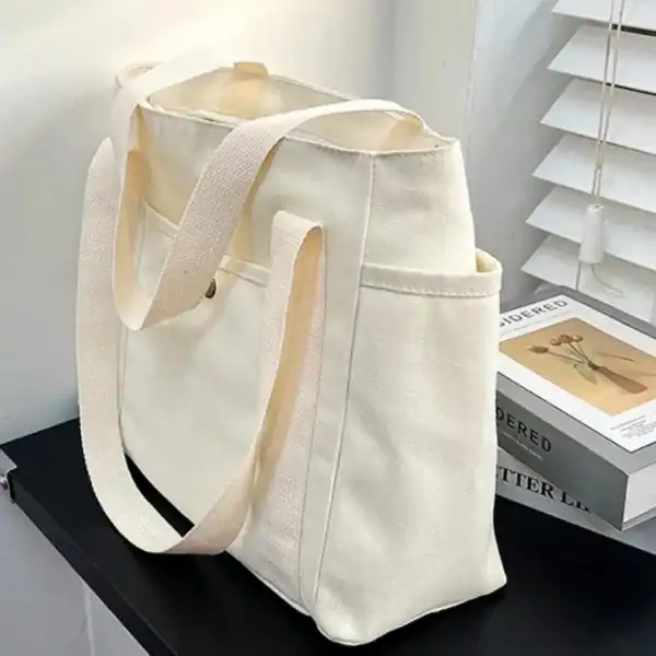 Krämvit canvas shoppingväska med långt handtag, ideal för daglig användning och shopping.