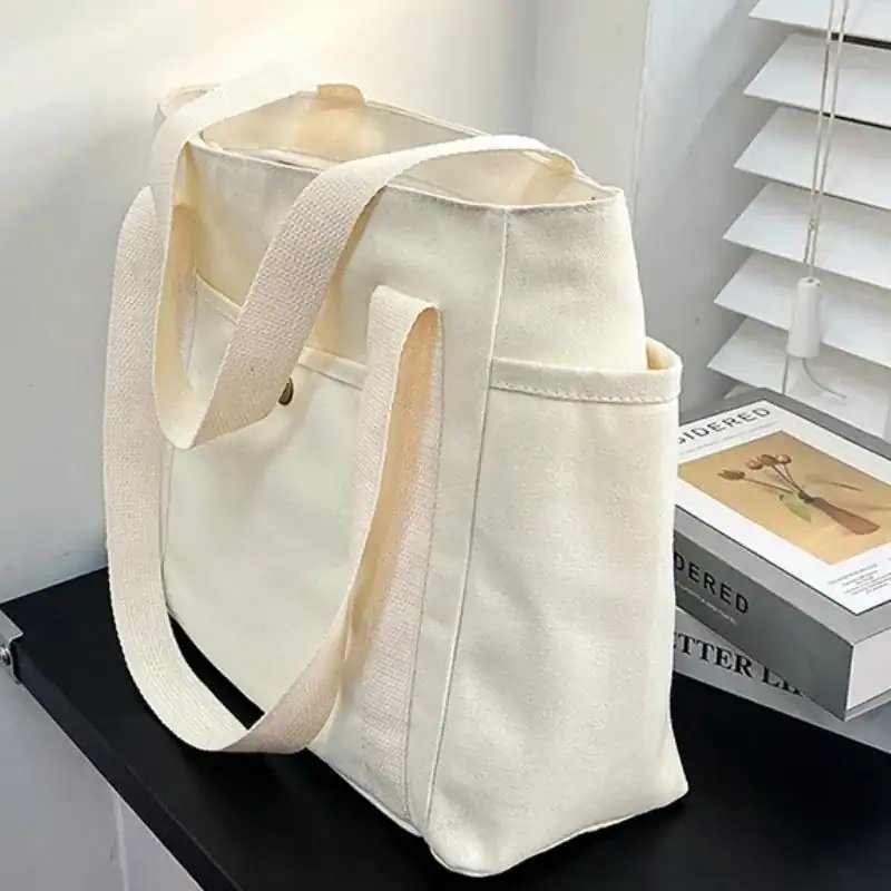 Krämvit canvas shoppingväska med långt handtag, ideal för daglig användning och shopping.
