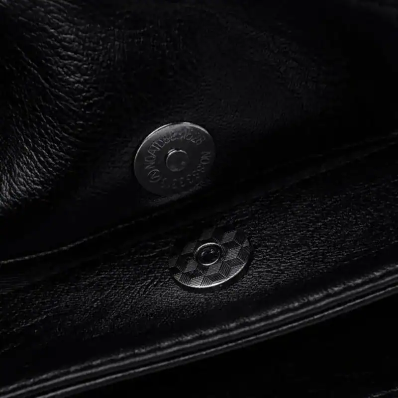 Krämvit crossbody väska, svart läder, detalj och knapp.