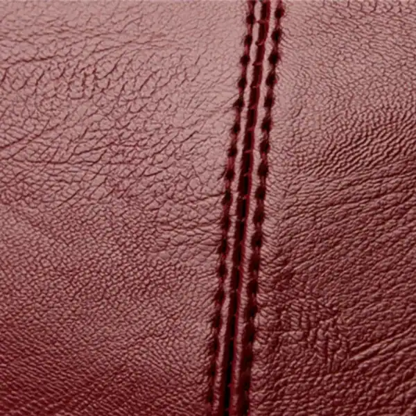 Krämvit crossbody väska, närbild på läder och kontrastnässning.