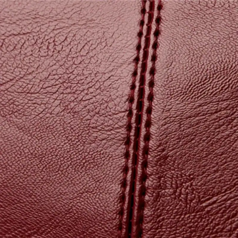 Krämvit crossbody väska, närbild på läder och kontrastnässning.