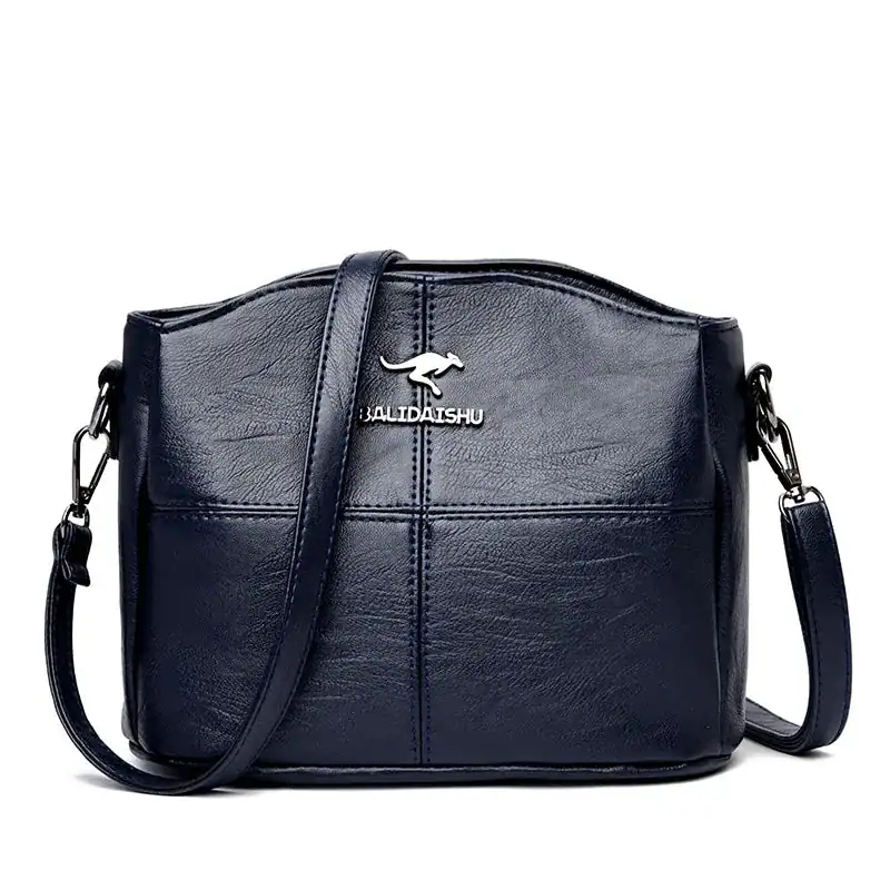 Krämvit crossbody väska, svart läder, axelväska med metalldetalj.