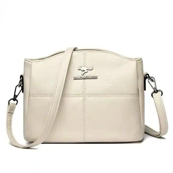 Krämvit crossbody väska med detalj och justerbar axelrem.