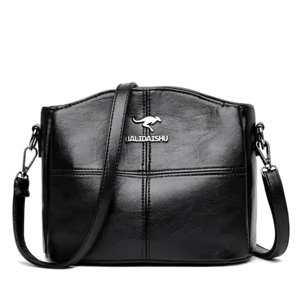 Krämvit crossbody väska, svart läder, axelväska med metallplåt och detalj.
