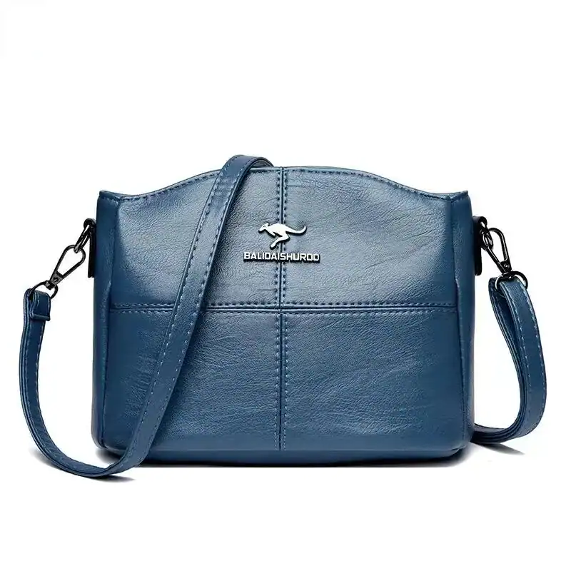 Krämvit crossbody väska i blått läder med axelrem och logo.