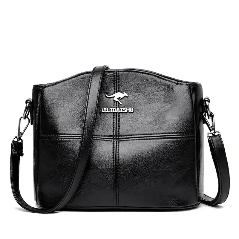 Krämvit crossbody väska, svart läder, axelväska med metallplåt och detalj.