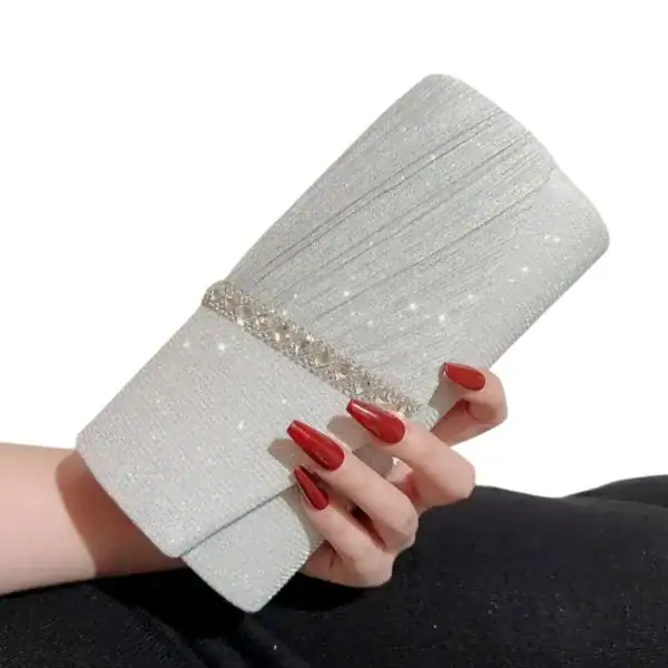 Krämvit glitterclutch med kristallbesättningsband och röd nagellack.