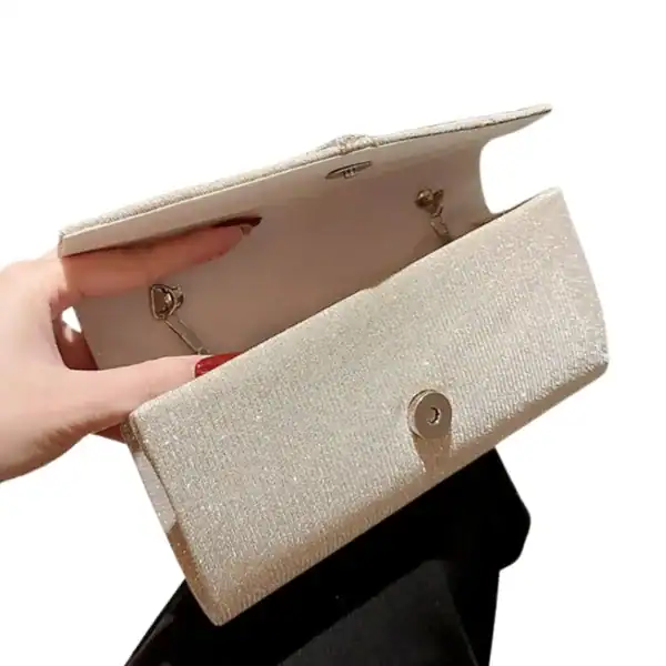 Krämvit glitterclutch med glittrig yta och metalliskt snäppa.