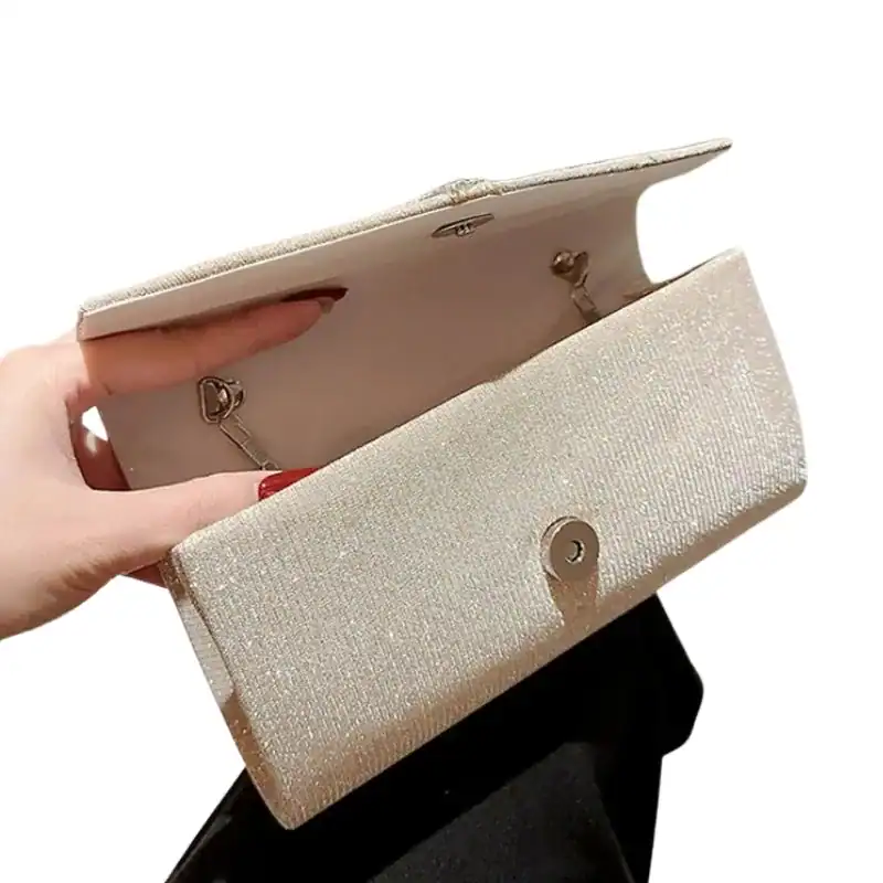 Krämvit glitterclutch med glittrig yta och metalliskt snäppa.