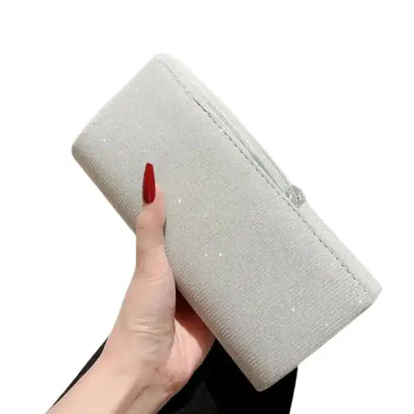 Krämvit glitterclutch i hand, elegant och perfekt för festliga tillfällen.