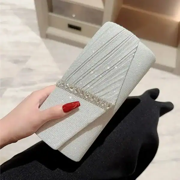 Krämvit glitterclutch med glittrig textur och kristallbesättning, perfekt för festliga tillfällen.