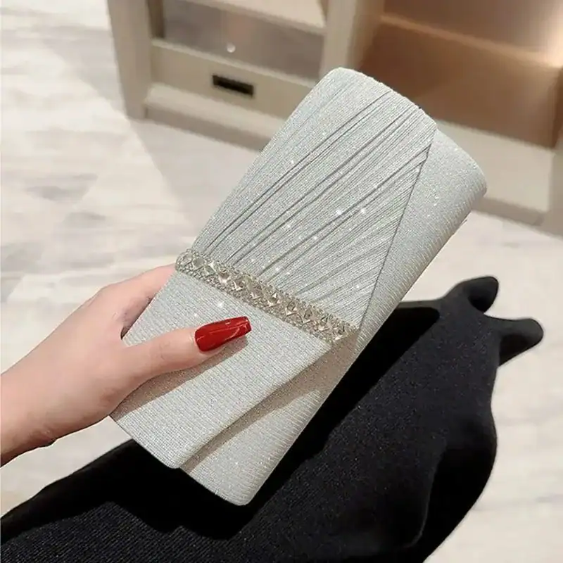 Krämvit glitterclutch med glittrig textur och kristallbesättning, perfekt för festliga tillfällen.
