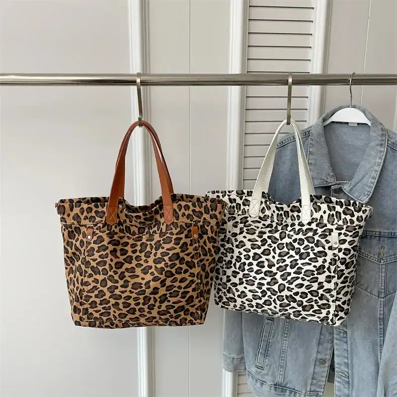 Leopard mönster axelväska i två färger, beige och vit, hängande på garderob.