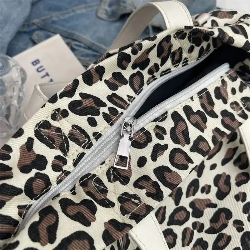 Leopard mönster axelväska med silverfärgad dragkedja och vitt handtag.