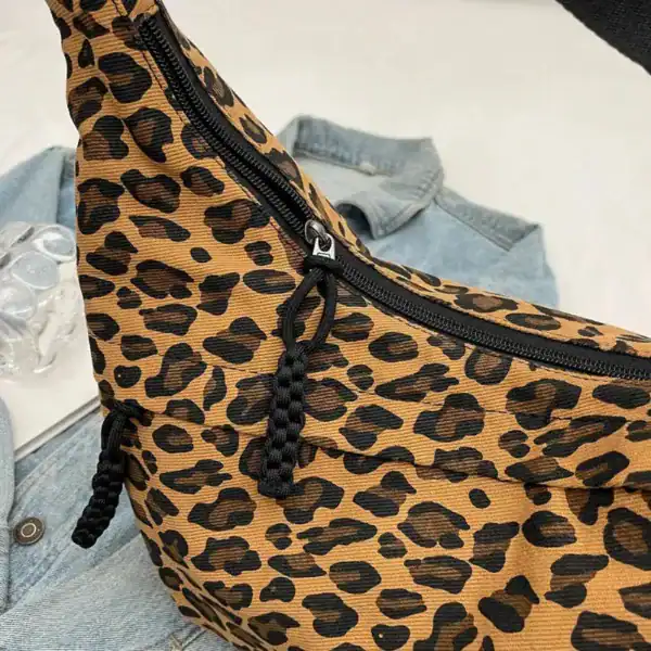 Leopard mönster hobo axelväska med svart dragkedja och jeansbakgrund.