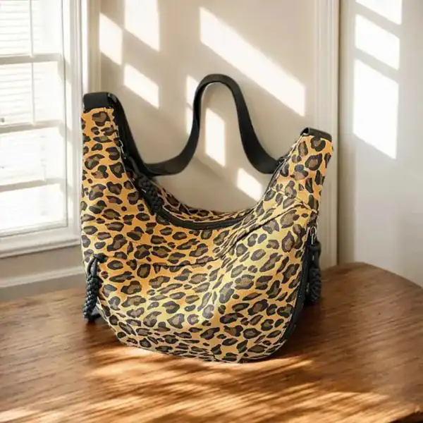 Leopard hobo axelväska med svarta handtag och soligt inomhusljus.