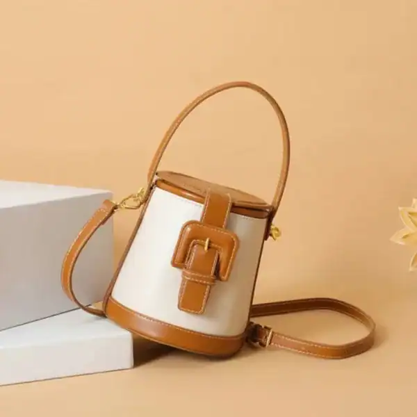 Liten brun hinkväska med vit kropp och gyllene detaljer.