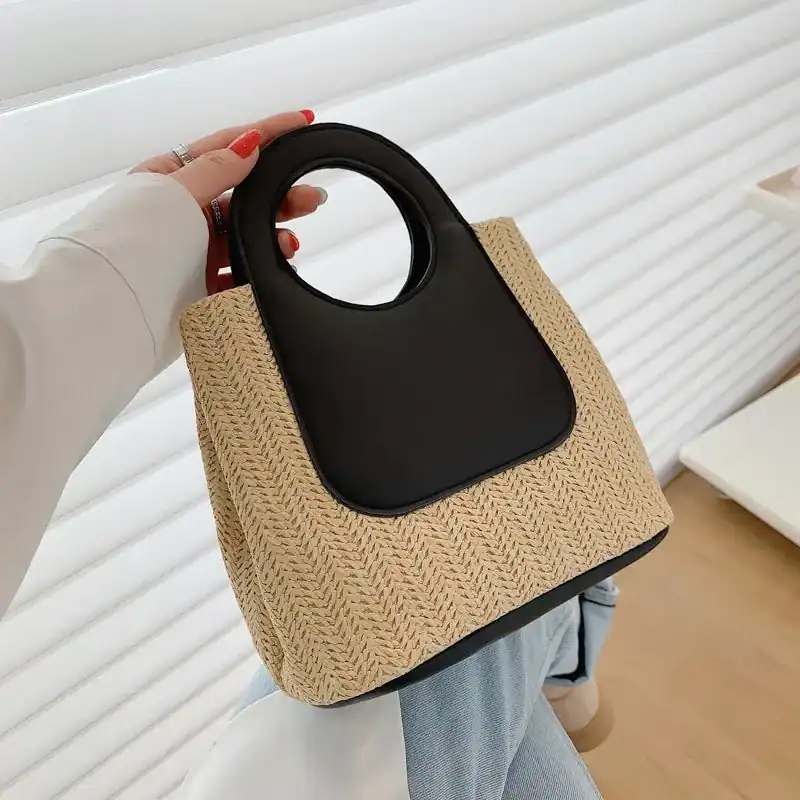 Liten svart korgväska med runt handtag, hakevävt material och modern design.