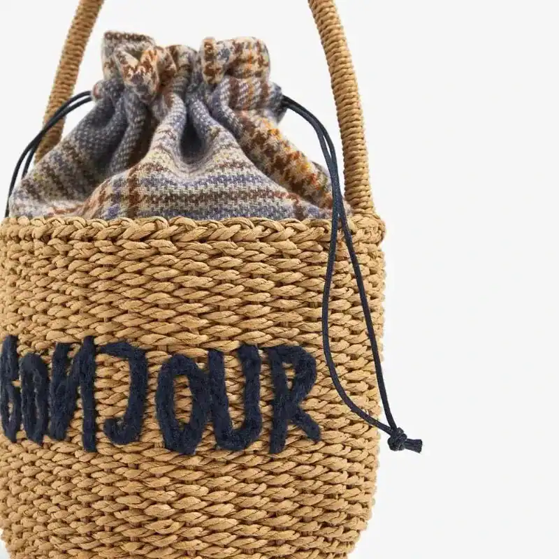 Liten stråväska med text 'Bonjou' och dragkedja, passar till sommar och strand.