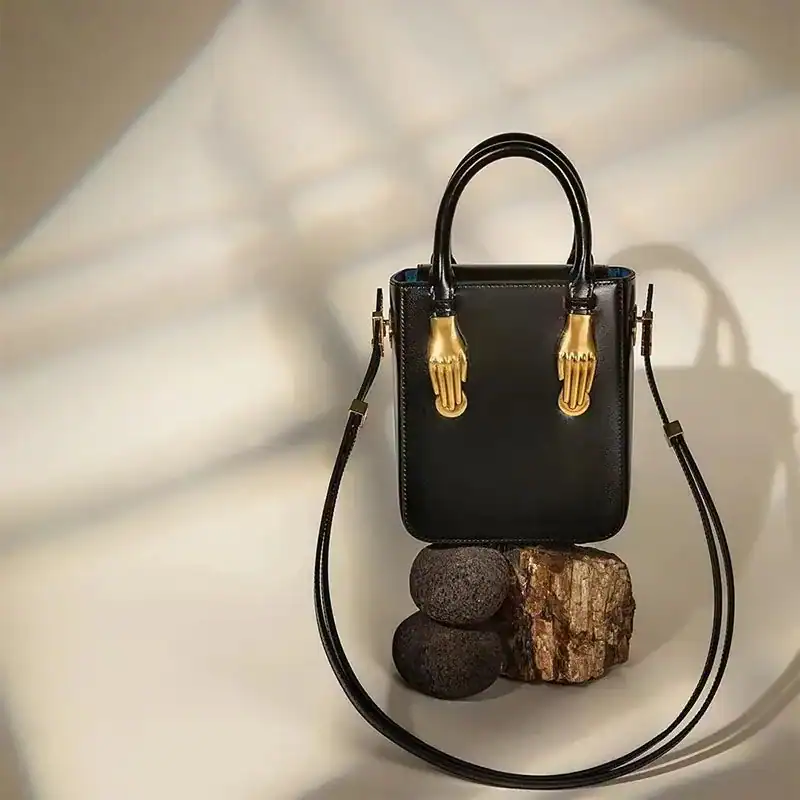 Liten svart shoppingväska med guldhandtag, elegant axelväska för kvinnor.