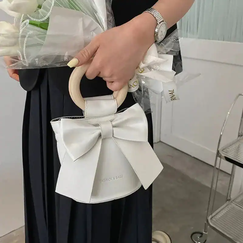 Ljusblå väska med stor rosett och runt handtag, modeaccessoarer för kvinnor.