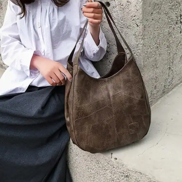 Metallic hobo väska i brunt, läderliknande material med texturerad yta och dubbla handtag.