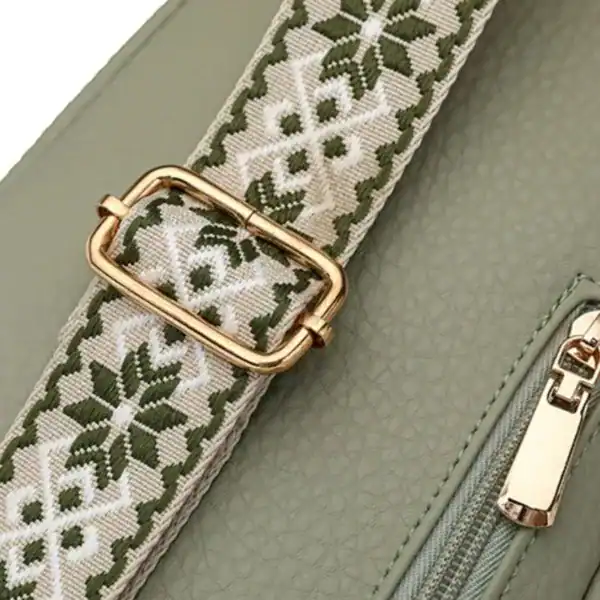 Mintgrön bröstväska med broderad axelrem och guldaktig snäppa.